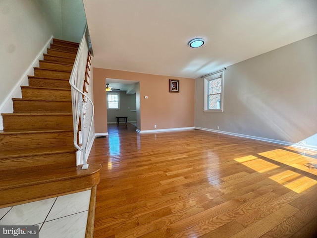 interior space featuring ceiling fan, light wood-type flooring, plenty of natural light, and stairs