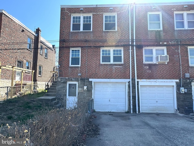 rear view of house featuring driveway, brick siding, and an attached garage