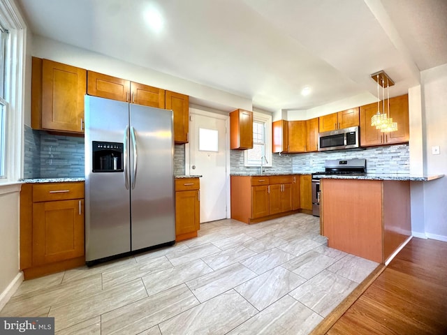 kitchen featuring stainless steel appliances, decorative backsplash, brown cabinetry, and a sink