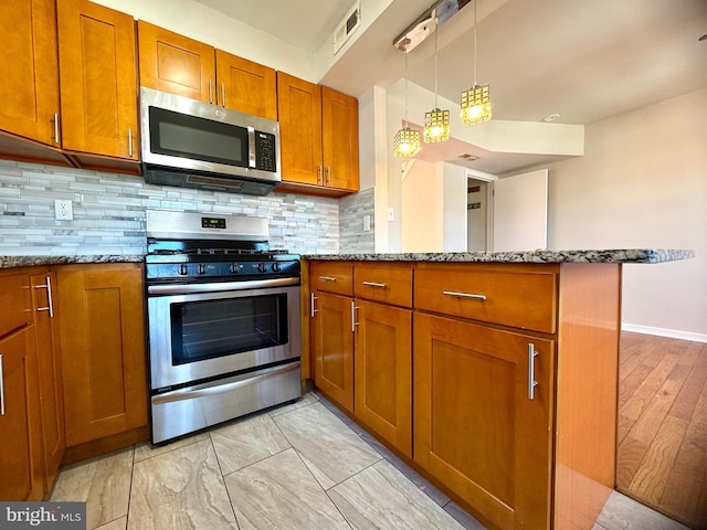 kitchen with stainless steel appliances, brown cabinetry, visible vents, a peninsula, and stone countertops