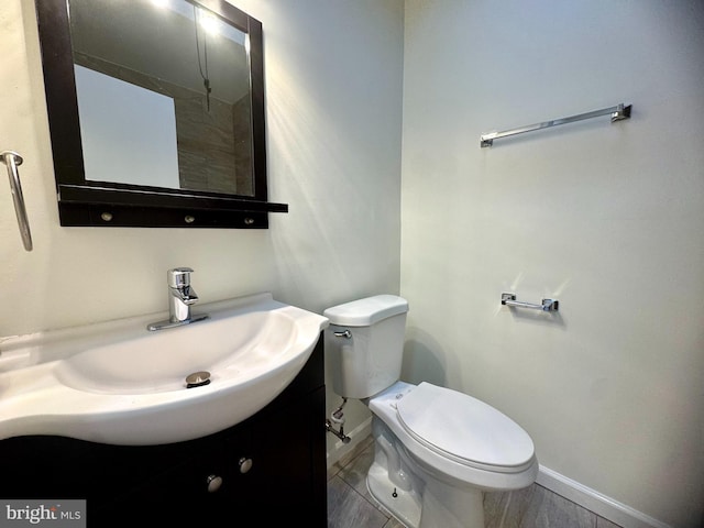 bathroom featuring toilet, vanity, and baseboards