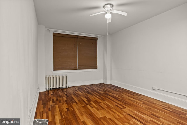 empty room featuring radiator heating unit, wood-type flooring, and ceiling fan