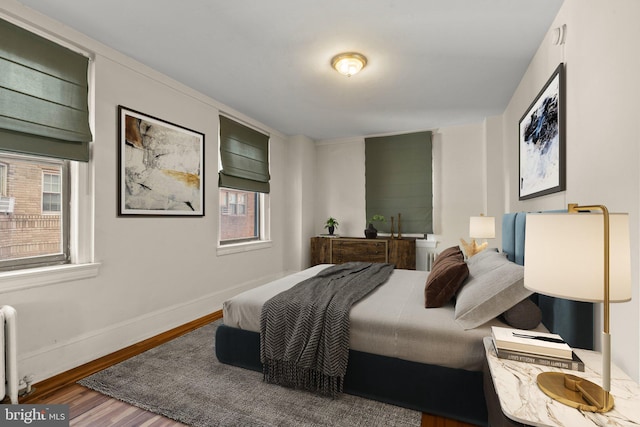 bedroom featuring radiator, wood-type flooring, and multiple windows