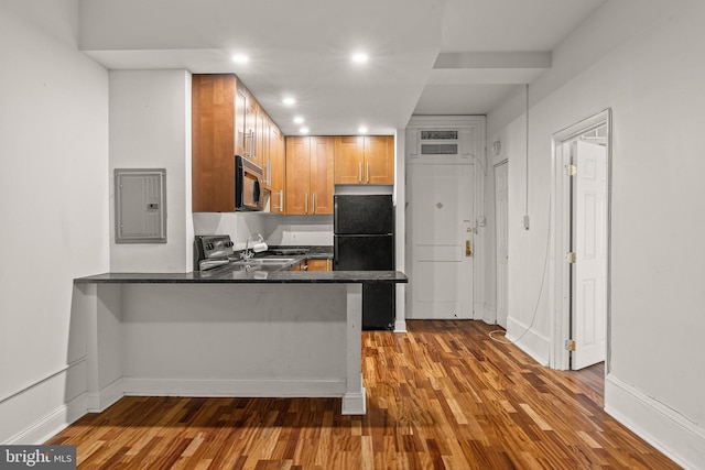 kitchen with dark hardwood / wood-style flooring, kitchen peninsula, a breakfast bar area, stainless steel appliances, and electric panel