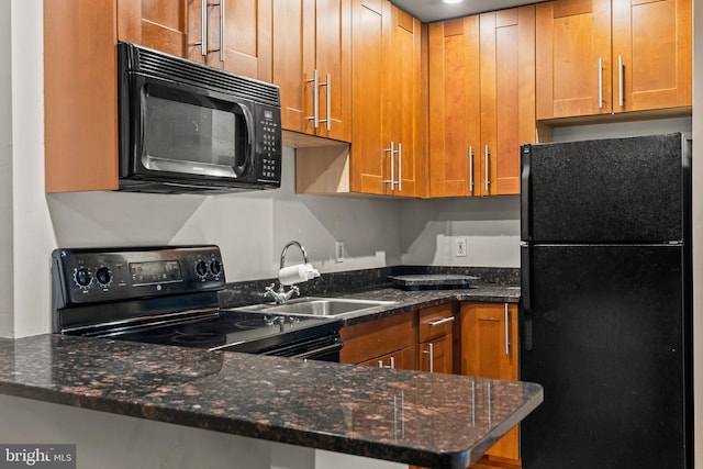 kitchen with kitchen peninsula, dark stone countertops, black appliances, and sink