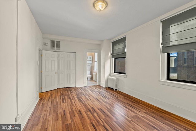 entrance foyer featuring wood-type flooring, radiator heating unit, and a wealth of natural light