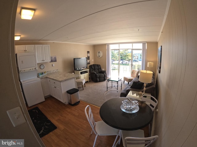 dining area with lofted ceiling, stacked washing maching and dryer, dark wood-type flooring, and wood walls