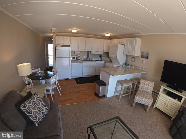 kitchen with white appliances, sink, dark hardwood / wood-style flooring, white cabinets, and ornamental molding