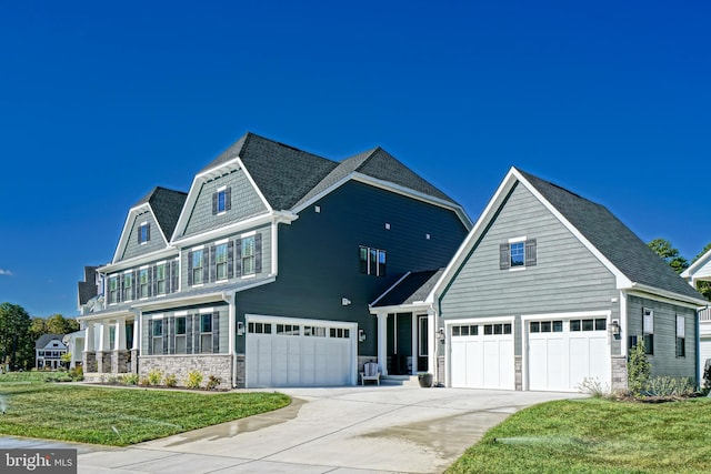 view of front of property with stone siding, concrete driveway, a front lawn, and a garage