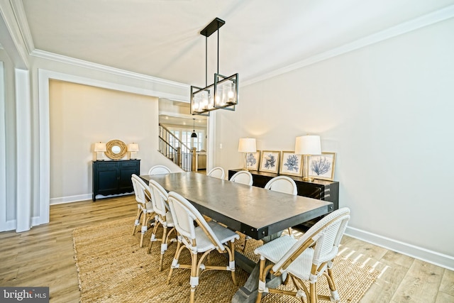 dining area with crown molding, stairs, and light wood-type flooring
