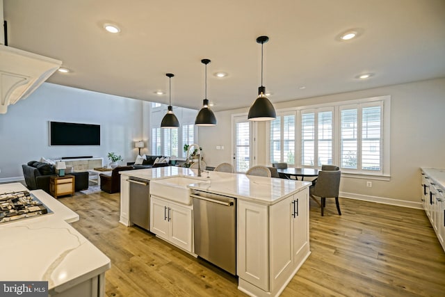 kitchen featuring light stone countertops, stainless steel appliances, light wood-type flooring, white cabinets, and open floor plan