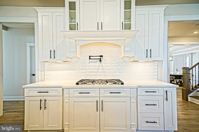 bar featuring stairway, decorative backsplash, stainless steel gas cooktop, and dark wood-type flooring