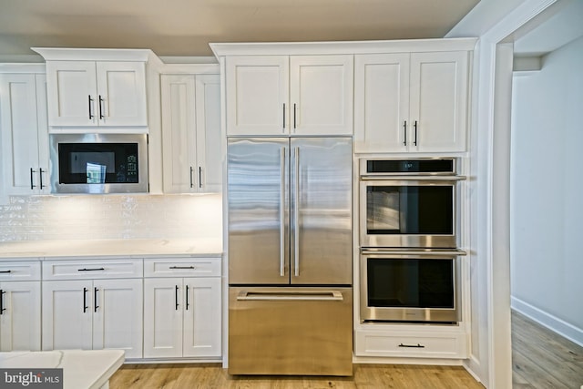 kitchen with light hardwood / wood-style flooring, white cabinetry, and built in appliances