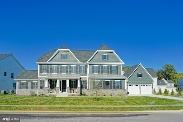 craftsman house featuring covered porch, a front yard, concrete driveway, and stone siding