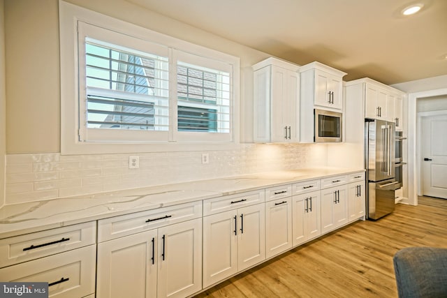 kitchen featuring light hardwood / wood-style flooring, white cabinetry, light stone countertops, and stainless steel appliances