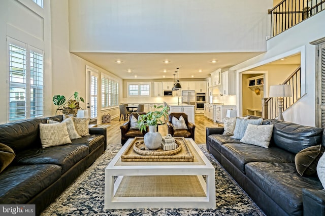 living room featuring light hardwood / wood-style floors, a healthy amount of sunlight, and a high ceiling