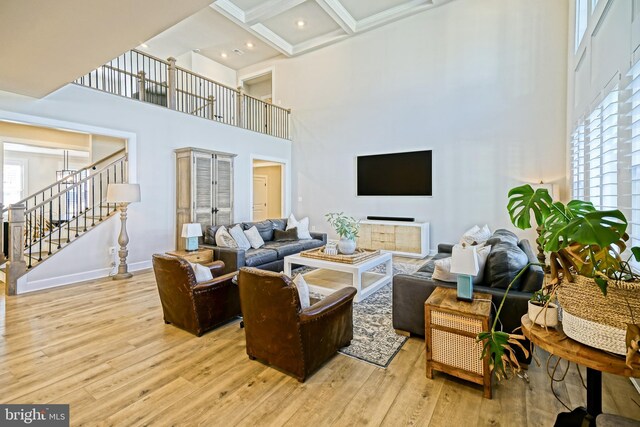 living area featuring a high ceiling, beam ceiling, stairs, light wood-style flooring, and baseboards