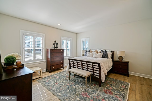 bedroom with baseboards, recessed lighting, light wood-style floors, and multiple windows