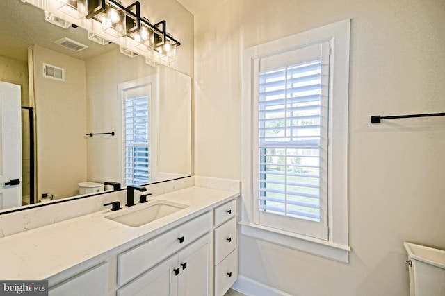 bathroom with toilet, visible vents, vanity, and a healthy amount of sunlight