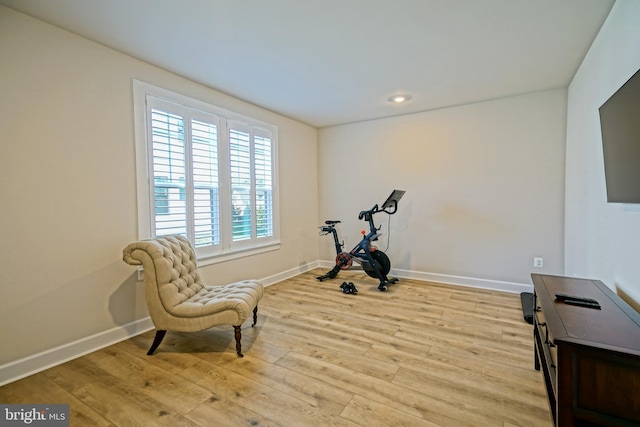 workout area featuring light wood finished floors and baseboards