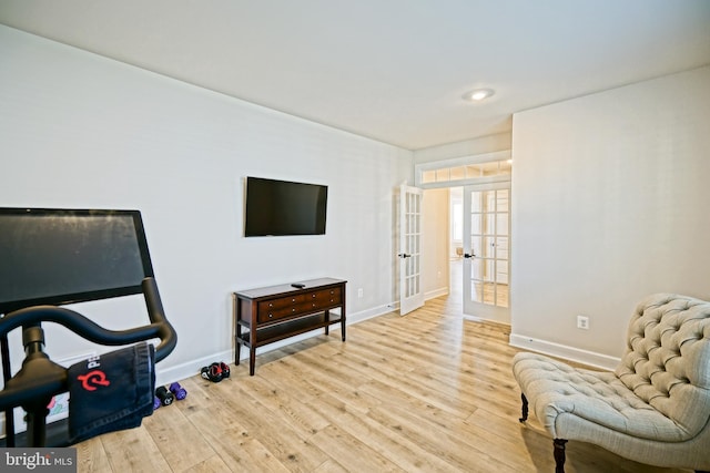 living area with baseboards, french doors, and light wood finished floors