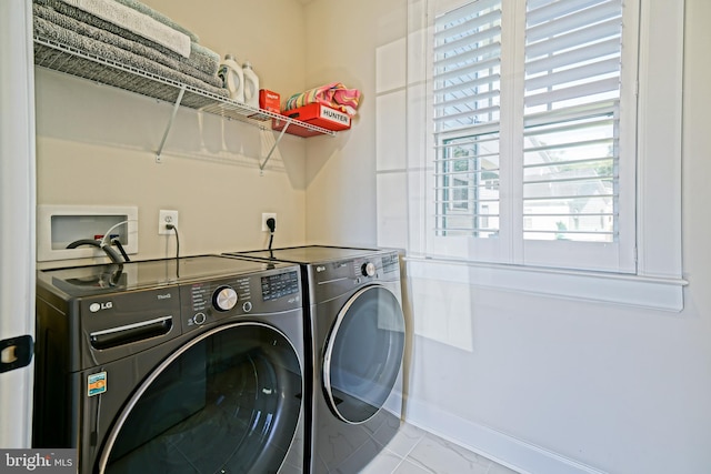 laundry area with separate washer and dryer and light tile patterned floors