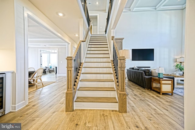 staircase with baseboards, ornamental molding, wood finished floors, and wine cooler