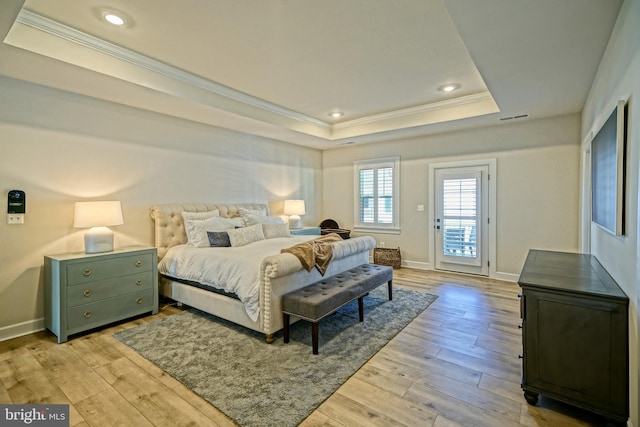 bedroom with light wood finished floors, a raised ceiling, access to exterior, visible vents, and ornamental molding