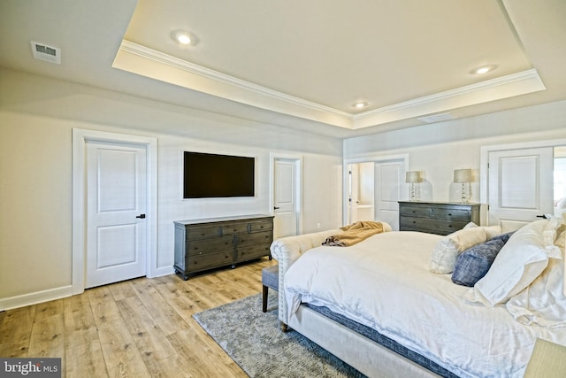 bedroom featuring light wood-style floors, baseboards, visible vents, a raised ceiling, and crown molding