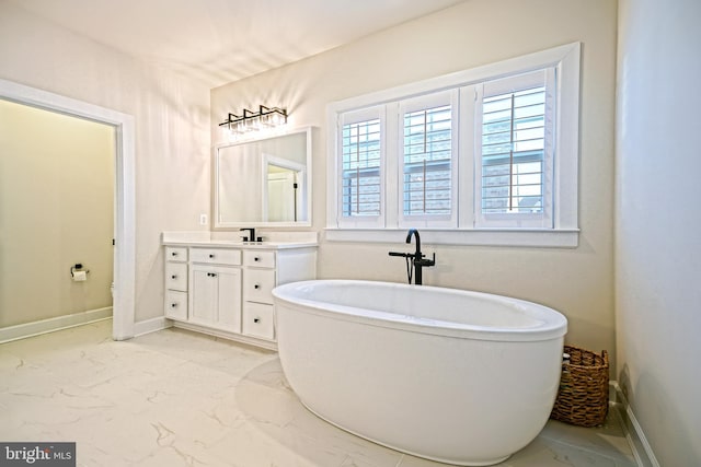 bathroom with baseboards, a freestanding tub, vanity, and marble finish floor