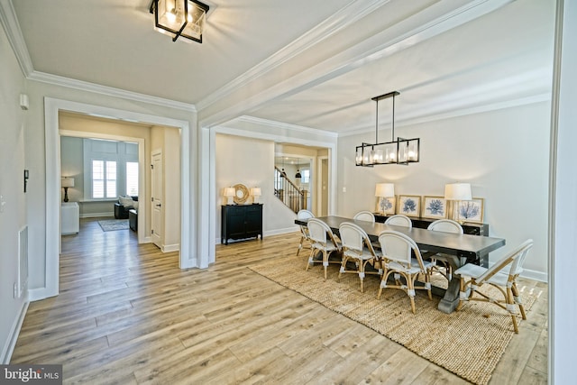dining room with light wood-type flooring, a notable chandelier, stairs, and crown molding