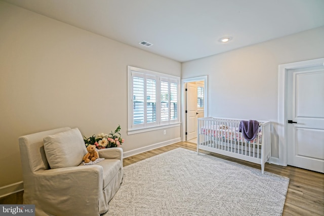 bedroom with wood-type flooring and a nursery area