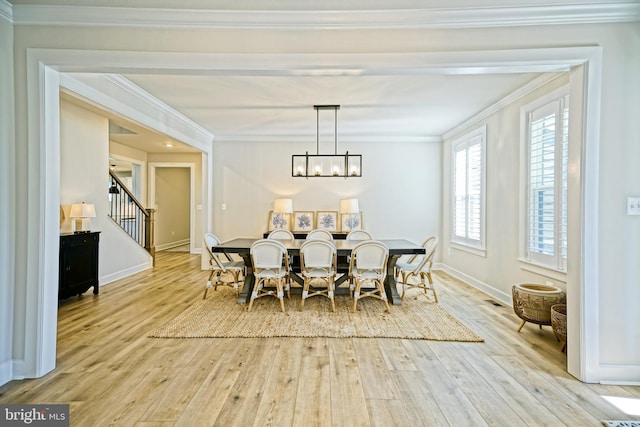 dining area featuring an inviting chandelier, light wood-type flooring, ornamental molding, and stairs