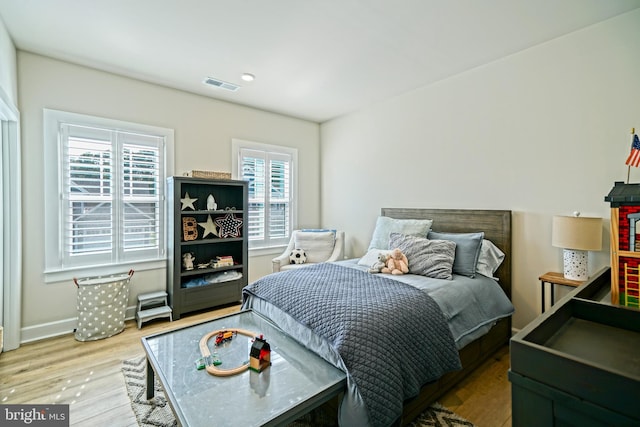 bedroom with baseboards, visible vents, and wood finished floors