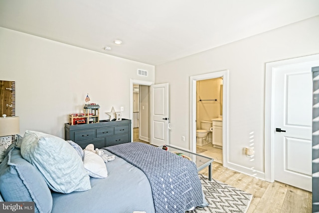 bedroom with visible vents, light wood-type flooring, ensuite bath, and baseboards