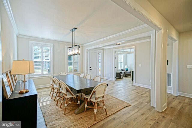 dining area with crown molding, light wood-style flooring, and baseboards