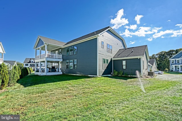 back of house with a balcony, cooling unit, and a lawn