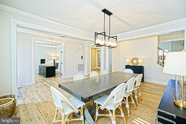 dining space with crown molding, a notable chandelier, and light wood-type flooring