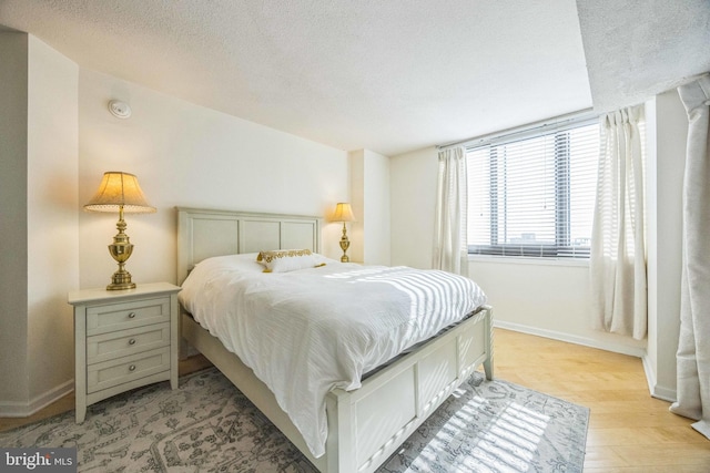 bedroom with a textured ceiling and light hardwood / wood-style floors