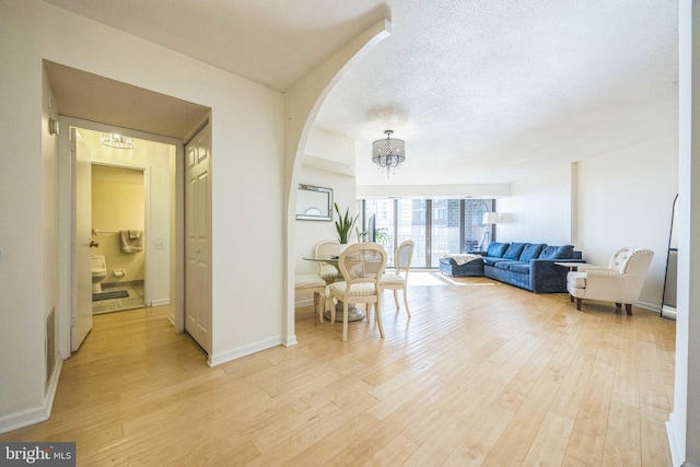 interior space with light hardwood / wood-style flooring, a notable chandelier, and a textured ceiling