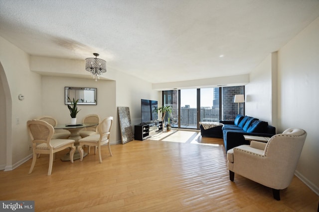 living room featuring a notable chandelier, a textured ceiling, and light hardwood / wood-style flooring