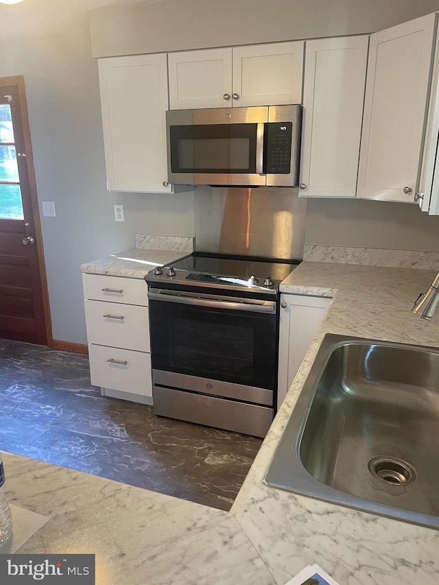 kitchen with appliances with stainless steel finishes, white cabinetry, and sink