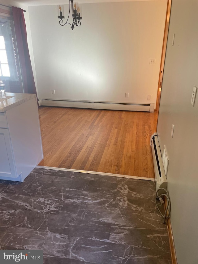 unfurnished dining area with an inviting chandelier, a baseboard heating unit, and dark hardwood / wood-style floors