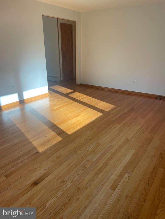 empty room with light hardwood / wood-style flooring and a baseboard heating unit