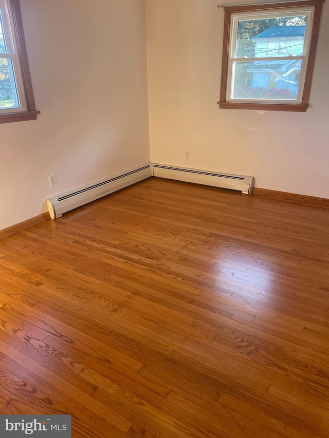 spare room with a baseboard heating unit and light wood-type flooring