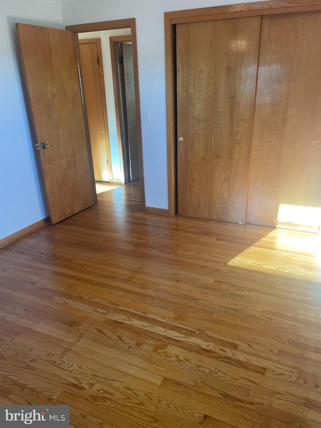 unfurnished bedroom featuring light hardwood / wood-style flooring and a closet