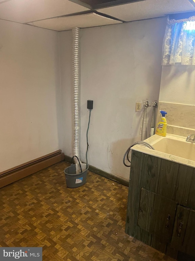 basement featuring sink and dark parquet flooring