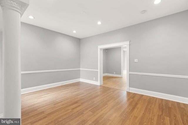 empty room with light wood-type flooring and decorative columns