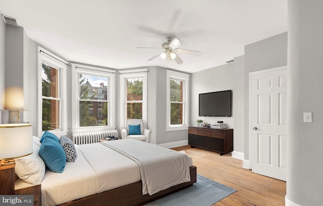 bedroom with light hardwood / wood-style flooring, radiator heating unit, and ceiling fan