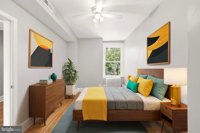 bedroom with radiator, wood-type flooring, and ceiling fan